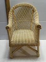 Front view of vintage small wicker chair with ruler for scale, showing woven wicker seat and lattice backrest.