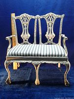 Front view of vintage heavy cast iron double doll bench showing ornate decorative backrest, curved legs, and upholstered seat.