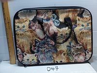 Closed view of rectangular bag with cat tapestry front and two handles, measuring approximately 12 in tall and 16.5 in wide with a ruler for scale.