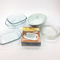 Set of 4 clear glass baking dishes and casserole with glass lid, plus boxed Micro Hot Plate on white background.