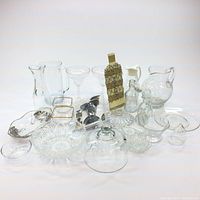Various glassware items grouped together showing pitcher, decanters, bowls, cake cover, and tea infuser.