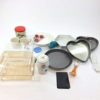 Overview of all kitchenware items including cake pans, bowl, cups, potpourri pot, plastic containers, utensils, and miscellaneous items.