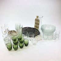Full lot of mixed glassware, serving bowls, decanter, decorative wine bottle cover, and trays shown together