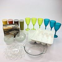 Photo of the pasta maker, assorted colored Tupperware glasses, green and blue goblets, various glass bowls, decorative glass plate, Pyrex casserole dish, and two white plastic ice trays.