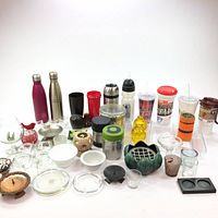 Wide view of the lot showing all items including thermoses, tumblers, candle holders, and other containers arranged on a white surface.