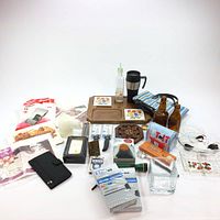 Photo of assortment of household, kitchen, and miscellaneous items including VHS tapes, serving trays, glass bottles, tote bag, and more.