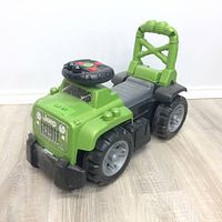 Photo of the green Jeep Big Blocks ride-on toy truck from front side angle on light wood floor.