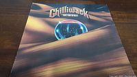 Front cover of vinyl album Lights From The Valley by Chilliwack showing artwork with reflective sphere and desert-like sand dunes.