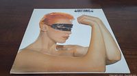 Front cover of the Eurythmics 'Touch' vinyl album featuring a person with orange hair and black mask.