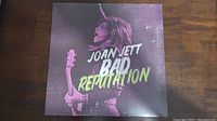 Front cover of the Joan Jett Bad Reputation vinyl record, showing Joan Jett with guitar in a purple-pink tone image.