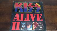 Front cover of the KISS Alive II vinyl album showing the band name and images of the four members in makeup.