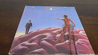 Front cover of the Rush Hemispheres vinyl album showing a man in a suit and a transparent woman on a large purple brain.
