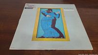 Front cover of Steely Dan Gaucho vinyl album showing the artwork of a dancing couple in blue and black on a white background with yellow border around illustration.