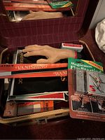Photo showing a realistic hand prop, multiple magic booklets, and magnesium fire starters package inside a red box.