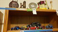 Full view of wooden shelf displaying model cars with decorative items on top