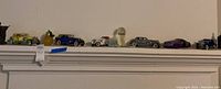 Wide shot of multiple diecast model cars on shelf including two-tone convertibles and sedans