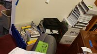 Boxes of Double A copy paper stacked, blue crate with binders and folders alongside other office supplies