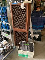 Front view showing the two wooden floor speakers with lattice grills and a nearby box of empty jewel CD cases.
