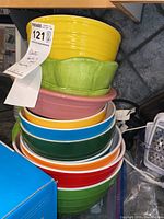 Stacked colorful plastic bowls in various sizes and colors including yellow, green, pink, blue, white, orange, and red
