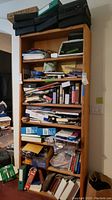 Full bookshelf filled with many books, boxes, and office materials, illustrating the quantity and variety of items involved.