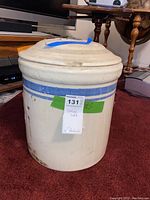 Full side view of ceramic crock with lid showing blue stripes and some stains/damage.