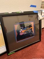 Angled view of the framed animation cel showing black frame and mounted cel