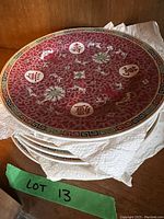 Stack of large red china plates with floral and Chinese character design