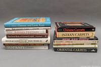 Two stacks of hardcover carpet and rug reference books showing titles and wear level