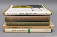 Stack of five vintage hardcover books with varying cover colors and titles visible on spines.