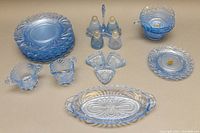 Overview photo showing total set comprising 8 luncheon plates stacked, salt and pepper shakers, bowls, divided dishes, and trays with original Cambridge Caprice Moonlight blue glassware stickers