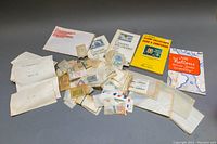 Overview of multiple stamp collector catalogues and numerous glassine envelopes containing assorted international stamps.