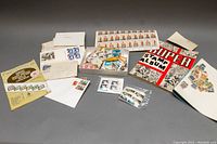Overview of the lot showing Super Stamp Album, envelopes with stamps, loose stamps in box, and stamp sheet.