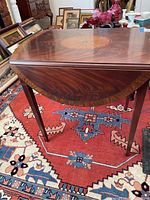 Front angle view of the wooden drop leaf table showing the curved drop leaf and wood grain finish.