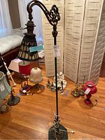 Full view of the metal floor lamp with Tiffany style shade and some surrounding lamps visible.