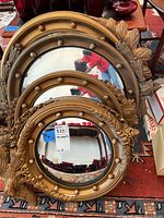Three nested gilt convex mirrors of varying sizes displayed on floor.