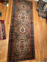 Full view of runner rug laid on hardwood floor showing three central medallions and border design