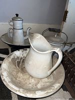 Four vintage items: ceramic pitcher and bowl with white finish and staining; enamel coffee percolator with black handle and lid; enamelled bowl with rust and chips