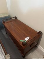 Wood cedar chest with closed lid showing the dark polished wood finish and decorative handles on lid and sides.