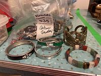 Photo showing multiple costume jewelry bracelets including metal, stone, and beaded styles arranged on a table.