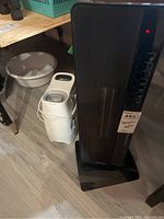 Honeywell humidifier and DeLonghi heater positioned side by side on a basement floor with shelving in the background.