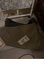 Folded inflatable bed inside green carry pouch with a lot sticker attached.