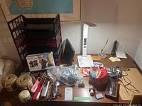 Overview photo showing desk lamp, rope coils, lighters, organizers, batteries, and various small items arranged on a table.