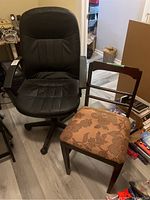 Photo of both chairs together, showing black faux leather office chair and wooden side chair with floral upholstered seat