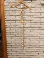 Full view of the ladder-style hanging wall art showing suspended shells and starfish against a white brick wall.