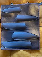 Front side of the black synthetic cutting tool carrier showing five individual sheath pockets for different sized knives or cutting tools.