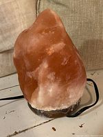 Front view of Himalayan salt lamp showing orange and white salt crystal with dark base and power cord.