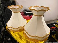 Pair of vintage cream lamp shades with gold trim and fringe shown together