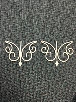 Pair of white wrought iron butterfly-shaped wall hangers on carpeted floor, showing scroll detail and diamond accent