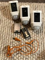 Overview of three cameras, two battery packs, charging dock and USB cable on rug