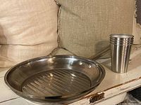 Shot of stainless steel pan and stack of five stainless steel cups on side table with couch background